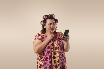 A Asian fat mother with a shocked expression looking at her phone. She is doing online shopping...