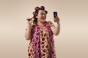 An Asian fat mother is happy looking at her phone. She is doing online shopping through her mobile...