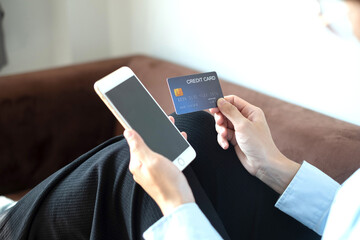 Asian girl shopping online holding credit and using smartphone enter their card number in the mobile phone app to purchase and payment in internet store