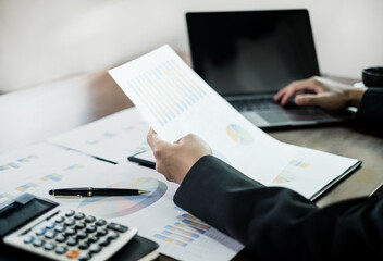 The businessman hand sits at their desks and calculate financial graphs showing results about their investments, planning a successful business growth process