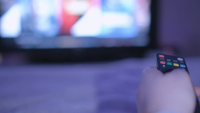 4K men hand holding the TV remote control and turn off smart tv. Channel surfing, focused on the hand and remote control. Internet TV at living room on holiday on sofa