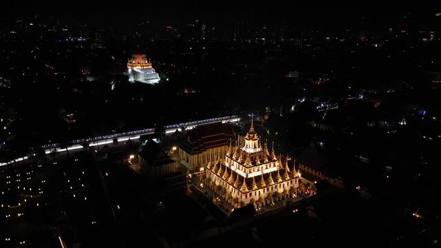 Aerial view of illuminated golden metal castle, Wat Ratchanatdaram Woravihara, Loha Prasat Temple at evening in Bangkok, Thailand