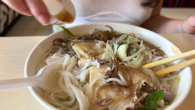 A young girl eats delicious pho bo soup with chicken in Vietnam in the mall fast cooking cheap food healthy traditional Vietnamese soup in Ho Chi Minh City. Saigon