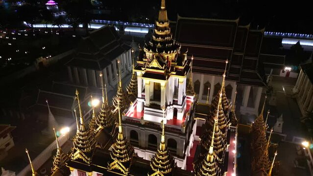 Aerial view of illuminated golden metal castle, Wat Ratchanatdaram Woravihara, Loha Prasat Temple at evening in Bangkok, Thailand