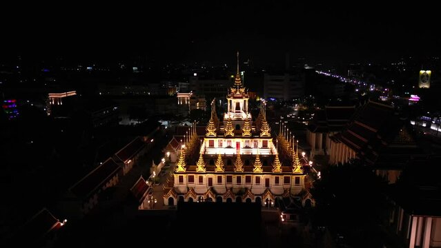 Aerial view of illuminated golden metal castle, Wat Ratchanatdaram Woravihara, Loha Prasat Temple at evening in Bangkok, Thailand