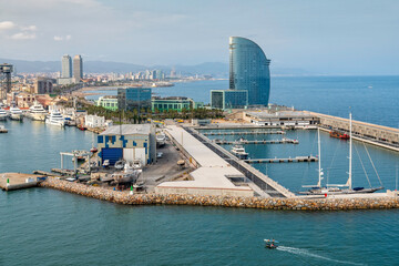 Barcelona city coastline with buildings and boats on sunny afternoon, Spain