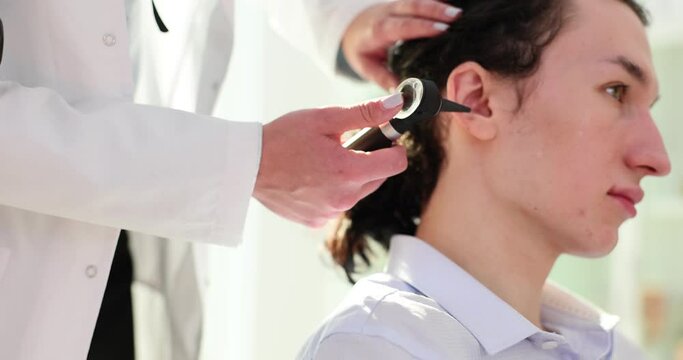 Otolaryngologist holds otoscope and examines patient ear