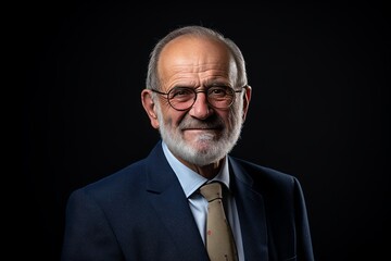 Portrait of a senior businessman in a suit on a black background.