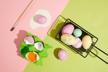 Pastel background featured a black basket of beautiful Easter eggs and an egg carton containing eggshell. Easter Sunday or Easter Day is the most important day of the year for Christians