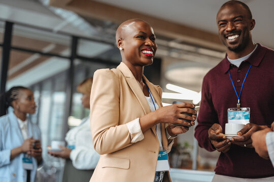Colleagues laughing and networking during coffee break at business conference