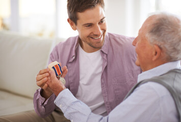 Senior, man and son or medal on sofa with war badge, pride and honor for military hero in living room of home. Elderly, veteran and retired soldier with medallion for service in army with happiness