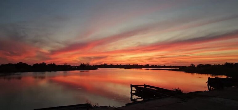 Impactante atardecer rojizo y reflejo del cielo en el r&iacute;o manso. 