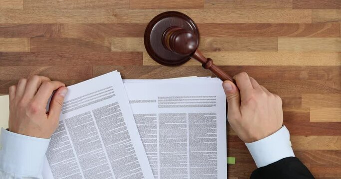 Male lawyer working with contract documents and wooden gavel on table in courtroom top view