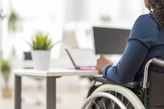 close up of disabled African American woman in a wheelchair writing on notebook on the table in the office