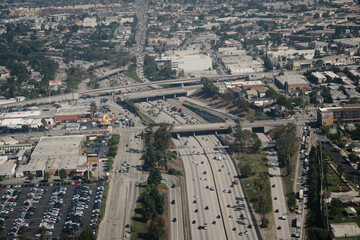 Aerial view of the freeway system in Los Angeles. Overpasses span several lanes, in a cityscape dominated by low-rise buildings.