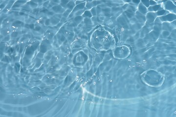 Blue water surface texture with ripples, splashes, and bubbles. Abstract summer banner background Water waves in sunlight with copy space cosmetic moisturizer micellar toner emulsion. Blue water wave.