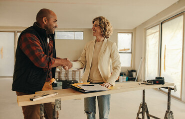 Successful partnership: Happy contractor and homeowner shaking hands in agreement for home renovation - obrazy, fototapety, plakaty