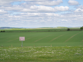 Red sign on open farmland stating out of bounds to unauthorised personnel indicating no public...