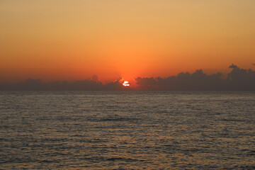 Sunset sky over the sea horizon. The sun breaks through the clouds above the sea horizon. Sea horizon at sunset. Sunset sea horizon