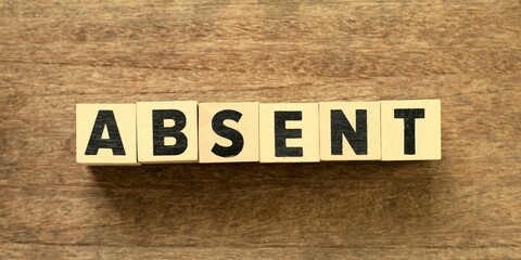 Word "ABSENT" made with wood building blocks.