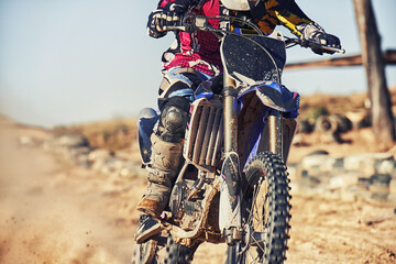 Person, motorcyclist and track with dirt bike for race, extreme sports or outdoor competition. Closeup or legs of expert rider on motorbike, scrambler or sand course for off road rally challenge