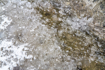 Obraz premium Melted snow and ice in early spring. Texture of wet snow on asphalt.