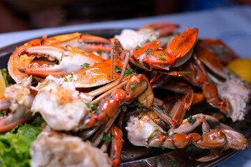 Seafood. Crabs tentacles on black plate with wite wine, lemon and herbs sauce on slate background. Top view.