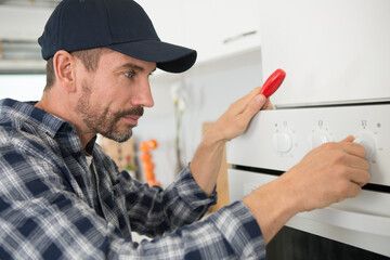 Naklejka na ściany i meble professional handyman repairing domestic oven in the kitchen