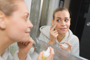 woman applying cream underneath her eye