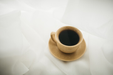 a cup of coffee stands on the windowsill with white curtains