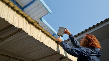 Woman installing solar lantern On the roof of the garage by yourself.
