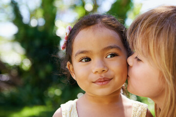Closeup, little children and cheek kiss in nature for fun, playing and bonding outside. Affection, outdoors and friendship with girl kids face for vacation or holiday in Sydney, Australia in summer