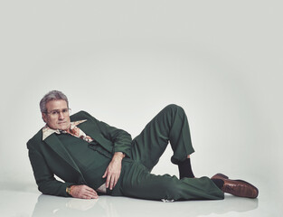 Studio, retro and mature model, fashion and lying on the floor with glasses and vintage style....