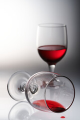 two glasses of red wine in different poses and on a light background.