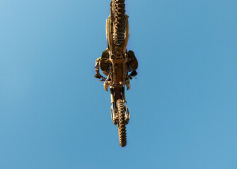 Motorcycle, jump and person on blue sky mockup with low angle for performance, extreme sports stunt...