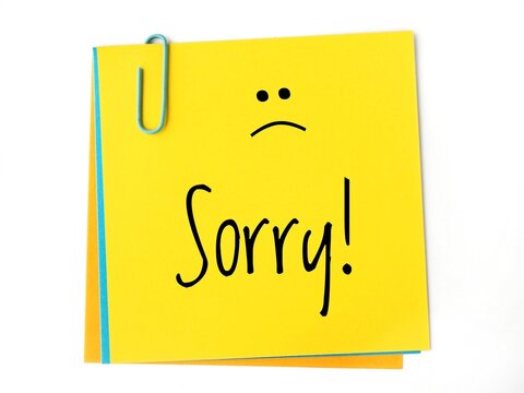 Sorry! handwritting message and sad face on a yellow sticky  note