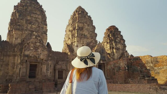 Back view of young asian woman tourist walking at Phra Prang Sam Yot, Lopburi Province looking the ancient site. Ancient Thailand. Travel concept
