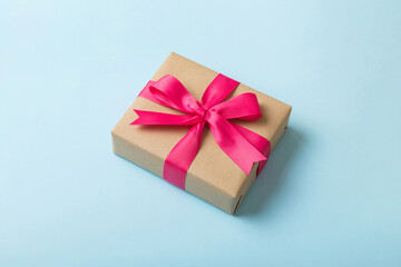 Wrapped christmas or other holiday handmade present in craft paper with colored ribbon. Present box, decoration of gift on table, top view with copy space