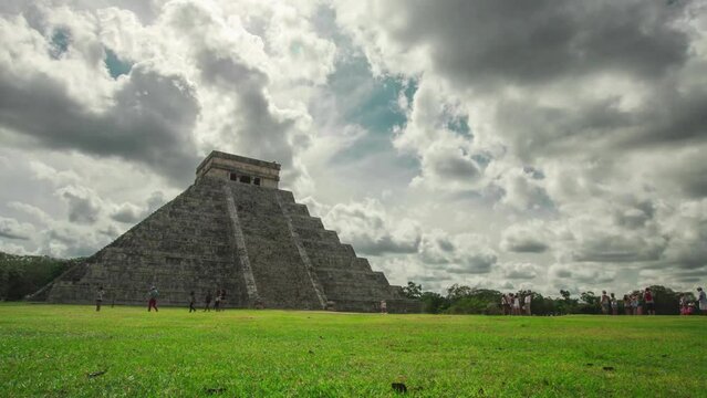Time lapse or hyperlapse of magnificent pyramid of chichen itza on yucatan peninsula in Mexico. Epic timelapse, clouds rushing by, blurred tourists and green grass.