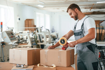 Packing the product. Handsome man is working at the factory of creating eco boxes