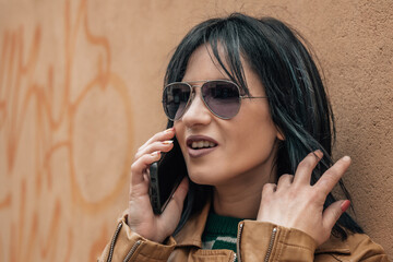 urban young woman talking with phone on street wall