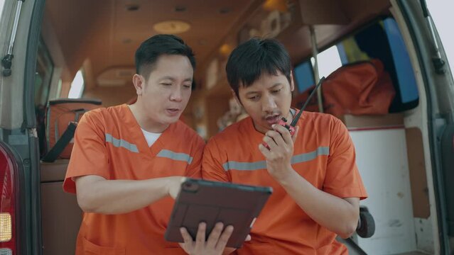 Rescue personnel preliminary talking by portable radio and working on tablet before being taken injured to the hospital. EMS Paramedic. First aid procedure. Emergency Medical First aid
