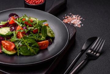 Delicious fresh salad with arugula, spinach, cucumber and cherry tomatoes in a ceramic plate