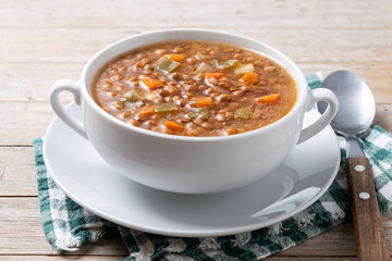 Lentil soup with vegetables in bowl on wooden table