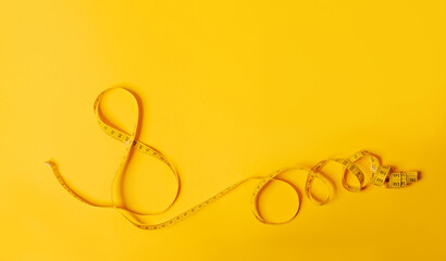 A measuring tape in the shape of a number eight on yellow background. Postcard for International Women's Day March 8. Holiday card. Eighth anniversary. Concept of creative hobby, sewing, weight loss