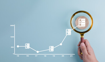 The man is holding magnifying glasses under a concept.Online documentation database, IT consultant being set up Virtual Document Management System with laptop,Software for archiving corporate files.