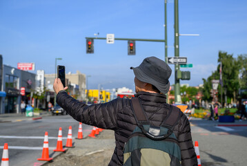 Tourist taking photos of downtown Anchorage using smartphones. Traffic cones and roadworks in Anchorage. Alaska.