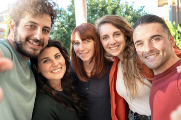 Obraz premium Young friends sharing a joyful moment taking a group selfie - Happiness and friendship in a casual outdoor setting
