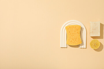 Fototapeta na wymiar Sponge, soap and lemon on beige background, space for text
