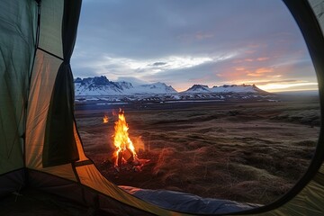 View from inside tourist tent. Night camping near mountains and hills. Burning campfire under beautiful evening sky.